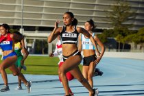Female track and field athletes running in competition on race track — Stock Photo