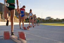 Женщины-легкоатлеты готовятся к стартовым блокам на треке — стоковое фото