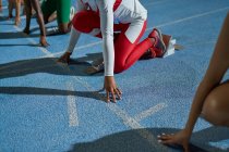Atletas de atletismo do sexo feminino na linha de partida na pista azul — Fotografia de Stock