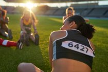 Female track and field athletes stretching before competition — Stock Photo