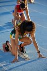 Atletas de atletismo do sexo feminino se preparando em blocos iniciais na pista — Fotografia de Stock