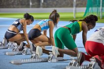 Atleti di atletica femminile ai blocchi di partenza in pista — Foto stock