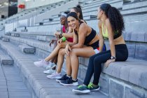 Atletas de atletismo do sexo feminino fazendo uma pausa nos degraus do estádio — Fotografia de Stock