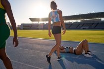 Cansado feminino pista e atleta de campo que estabelece na pista após a competição — Fotografia de Stock