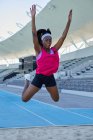 Atleta femminile di atletica leggera che salta lungo la sabbia — Foto stock