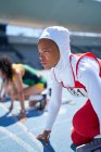 Atleta de pista y campo femenina enfocada en hijab en el bloque de inicio - foto de stock