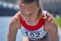 Close up focused female track and field athlete preparing for race — Stock Photo