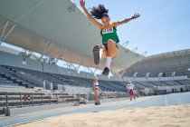 Atleta femminile di atletica leggera che salta lungo la sabbia — Foto stock