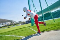 Female track and field athlete in hijab throwing discus — Stock Photo