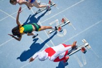 Female track and field athletes taking off from starting blocks — Stock Photo
