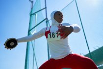 Determined female track and field athlete in hijab throwing discus — Stock Photo