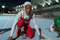 Atleta di atletica leggera femminile concentrata in hijab al blocco di partenza — Foto stock