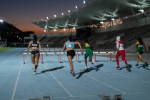 Женщины-легкоатлеты мчатся к препятствиям на стадионе — стоковое фото