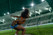 Female track and field athlete throwing discus at stadium competition — Stock Photo