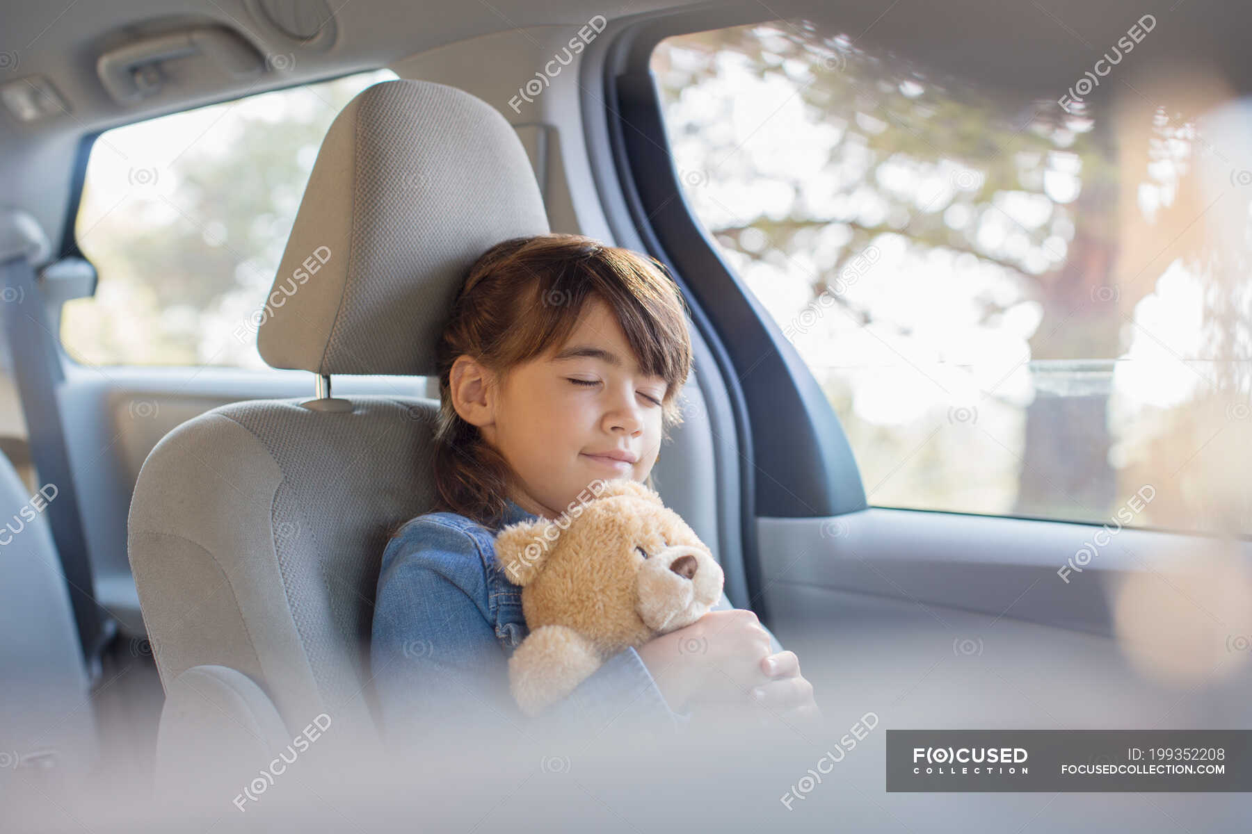 Girl with teddy bear sleeping in back seat of car — selective focus ...