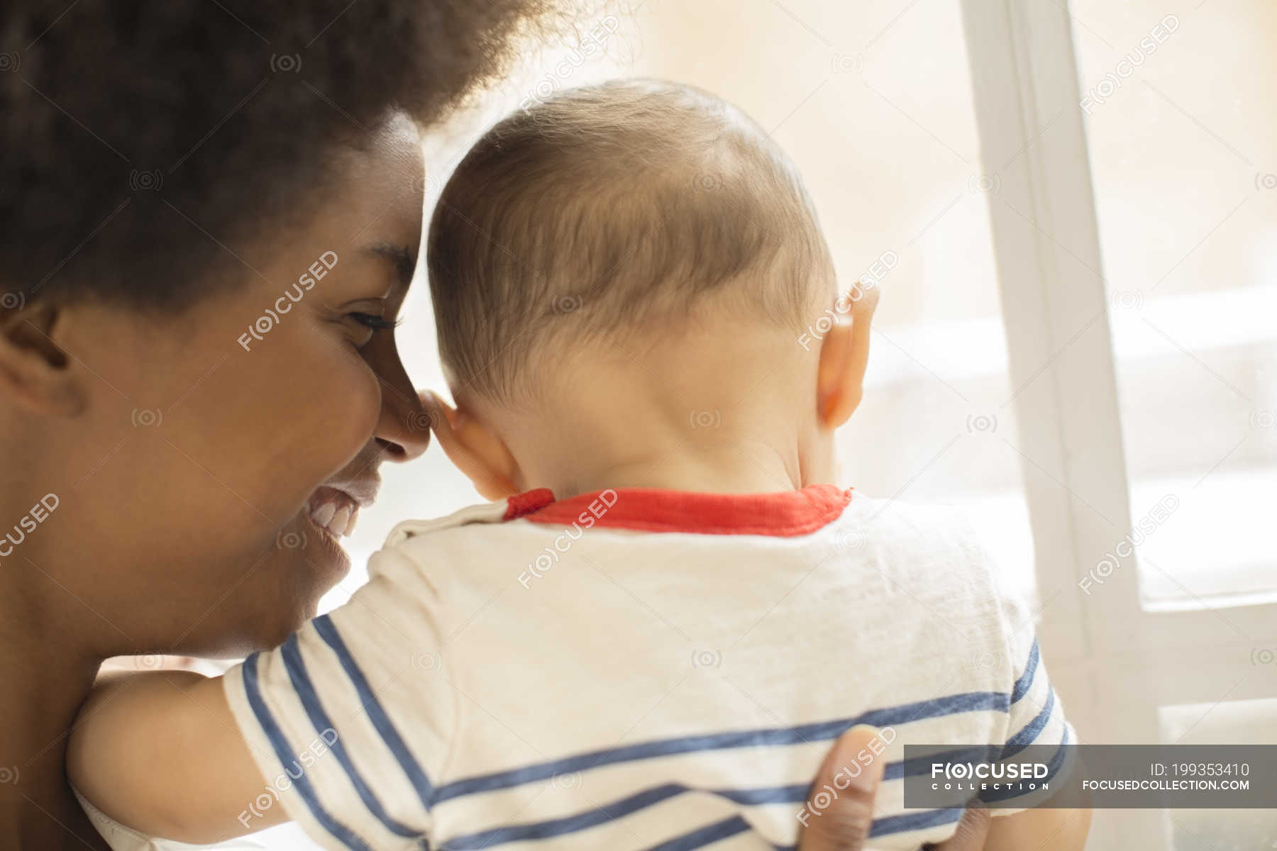Mother holding baby boy at home — head and shoulders, smiling Stock Photo 199353410