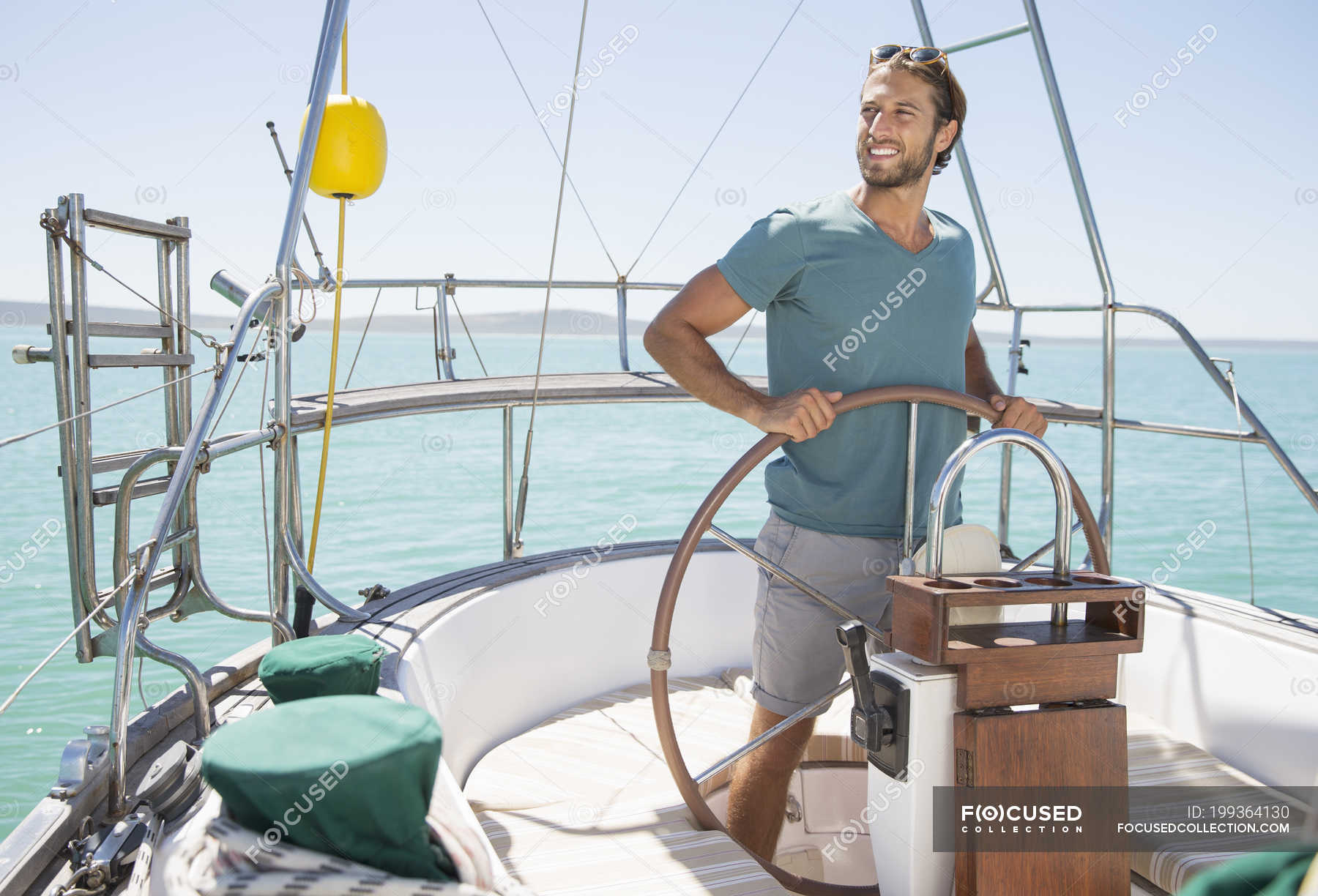 Man steering sailboat on water — three quarter length, ocean Stock