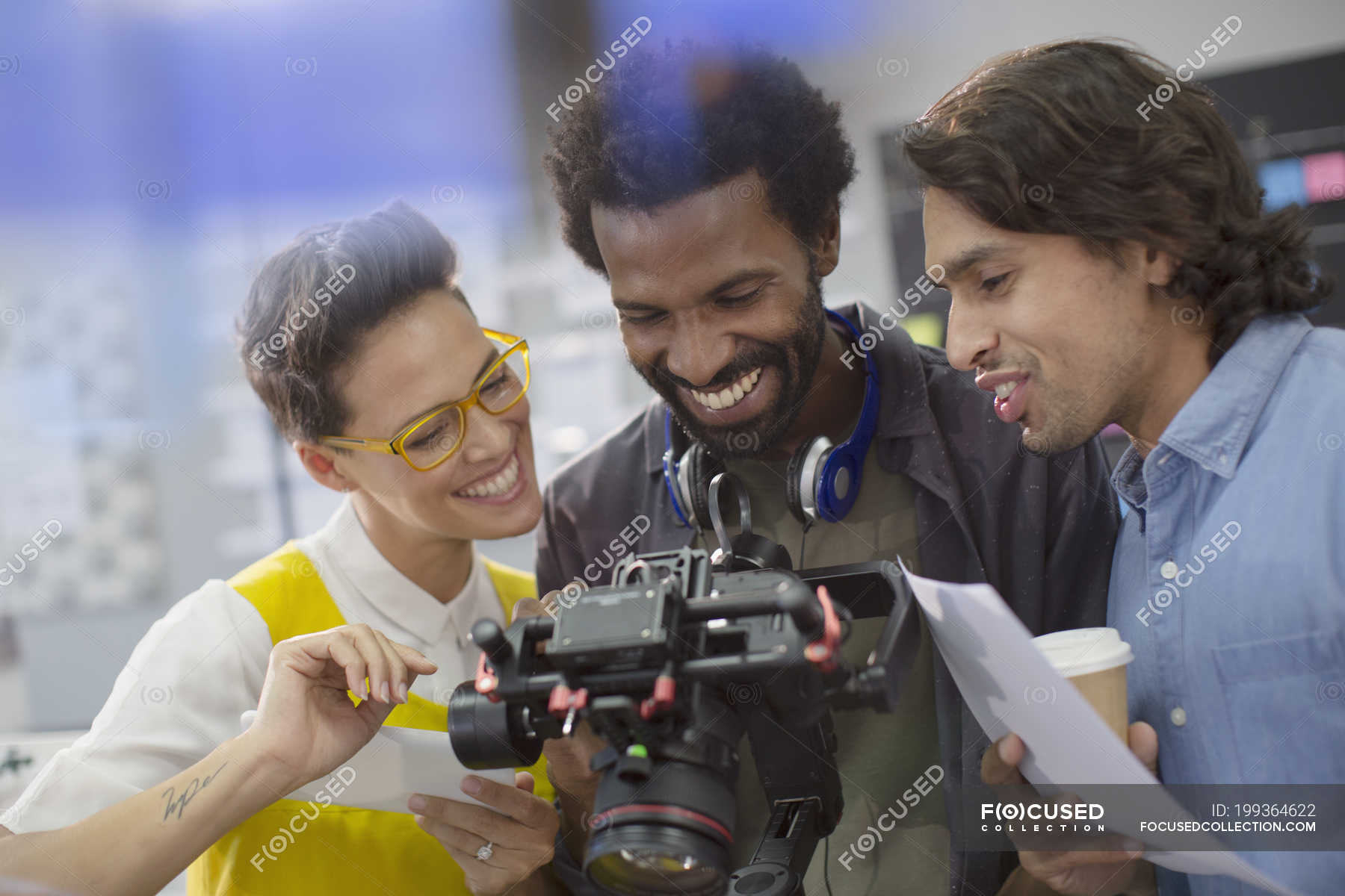 Smiling journalists and cameraman using digital camera — Creative ...