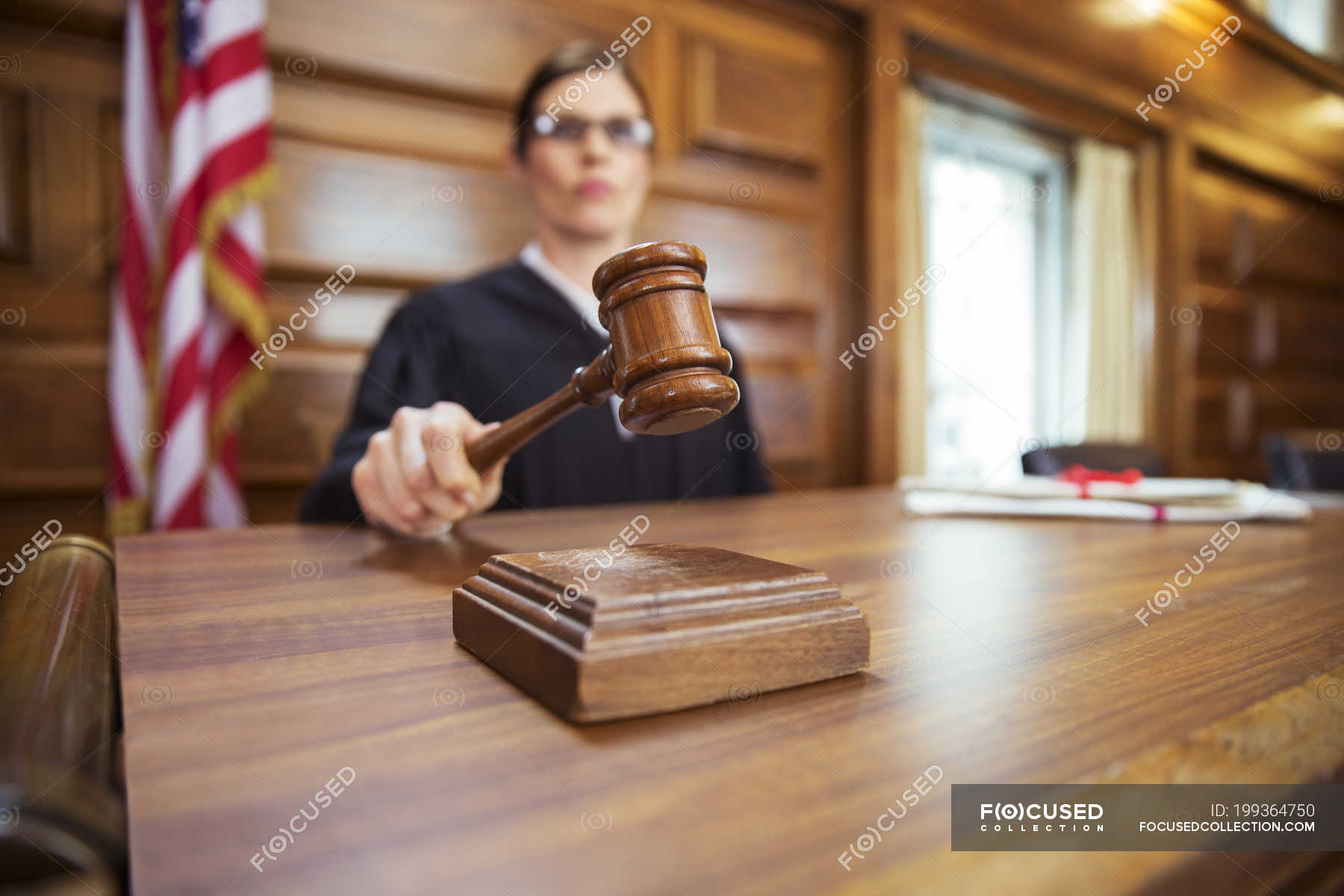 judge-banging-gavel-in-court-american-flag-indoors-stock-photo