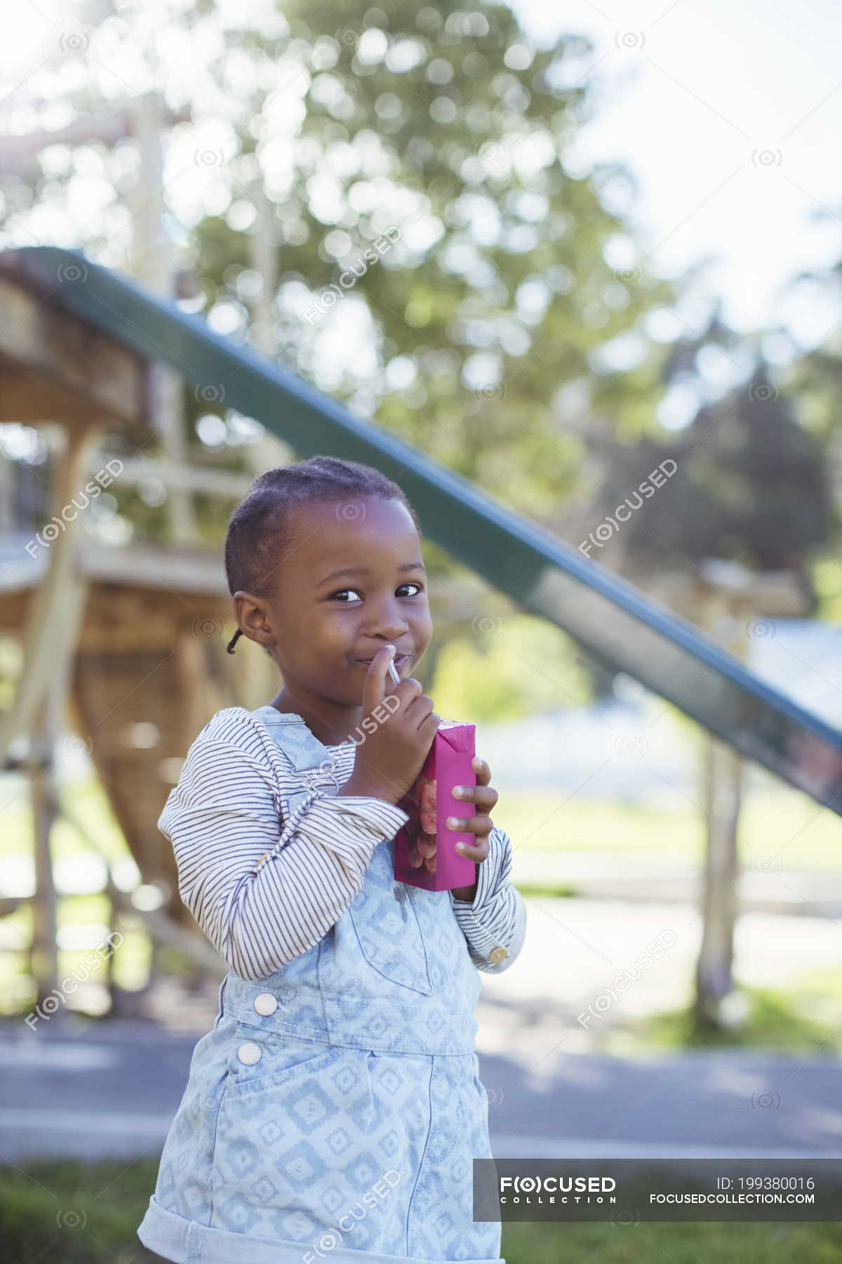 Chica beber jugo caja en el patio de recreo — aire libre, etnia