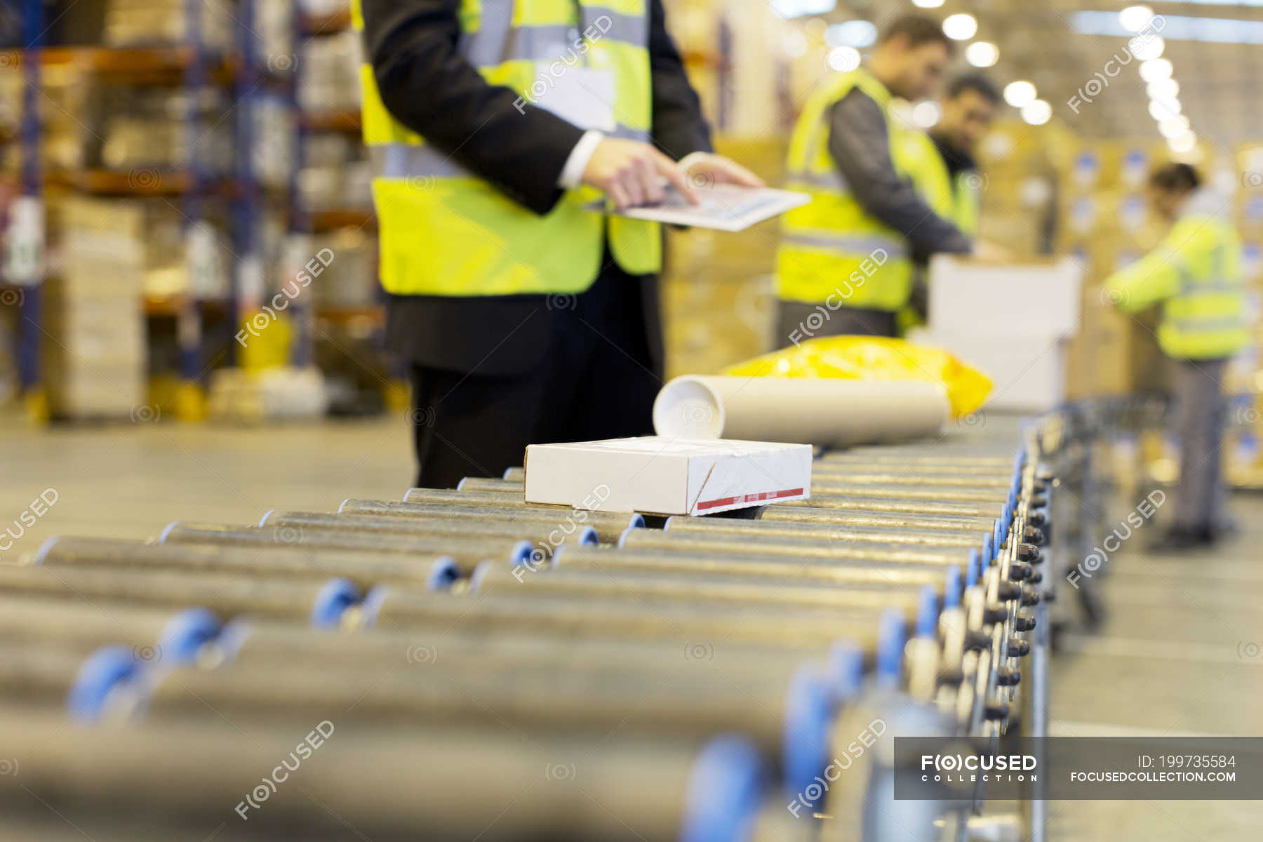 Workers checking packages on conveyor belt in warehouse — shipping
