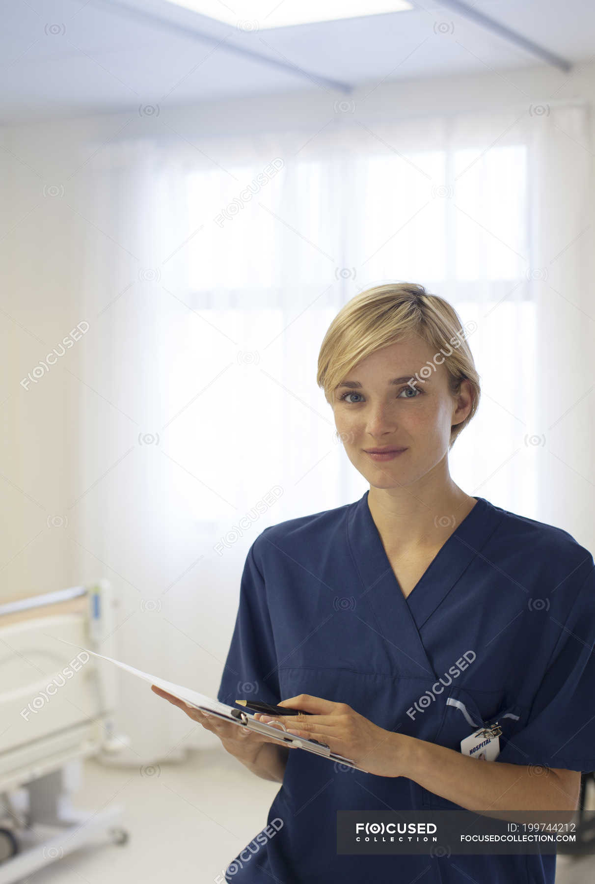 Nurse Reading Clipboard In Hospital Hallway — Indoors Success Stock