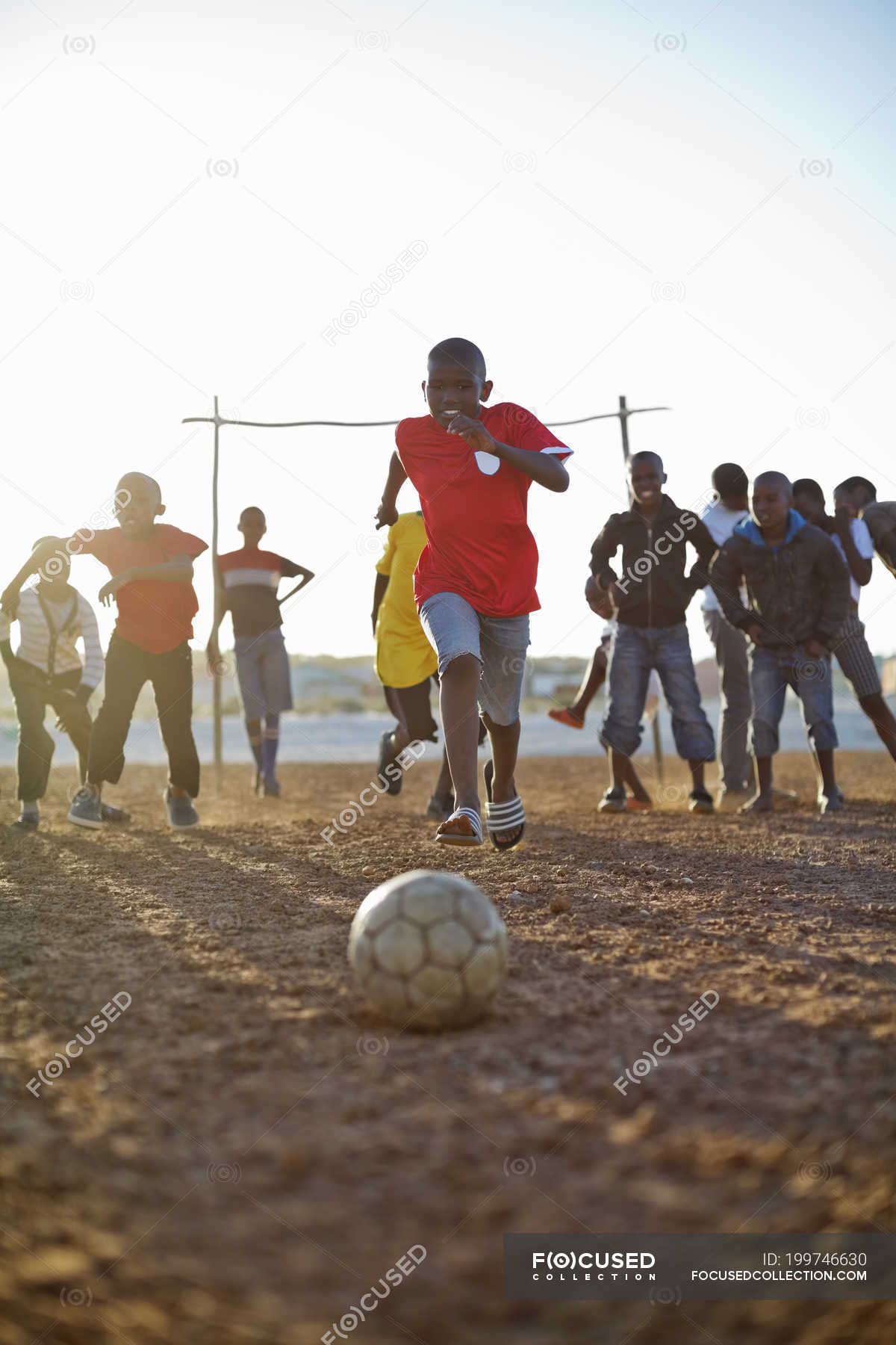 African boys playing soccer together in dirt field — space - Stock Photo | #199746630