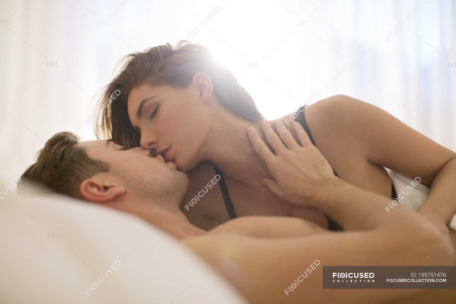 Young attractive couple kissing in bed — romance, wife - Stock Photo |  #199751476