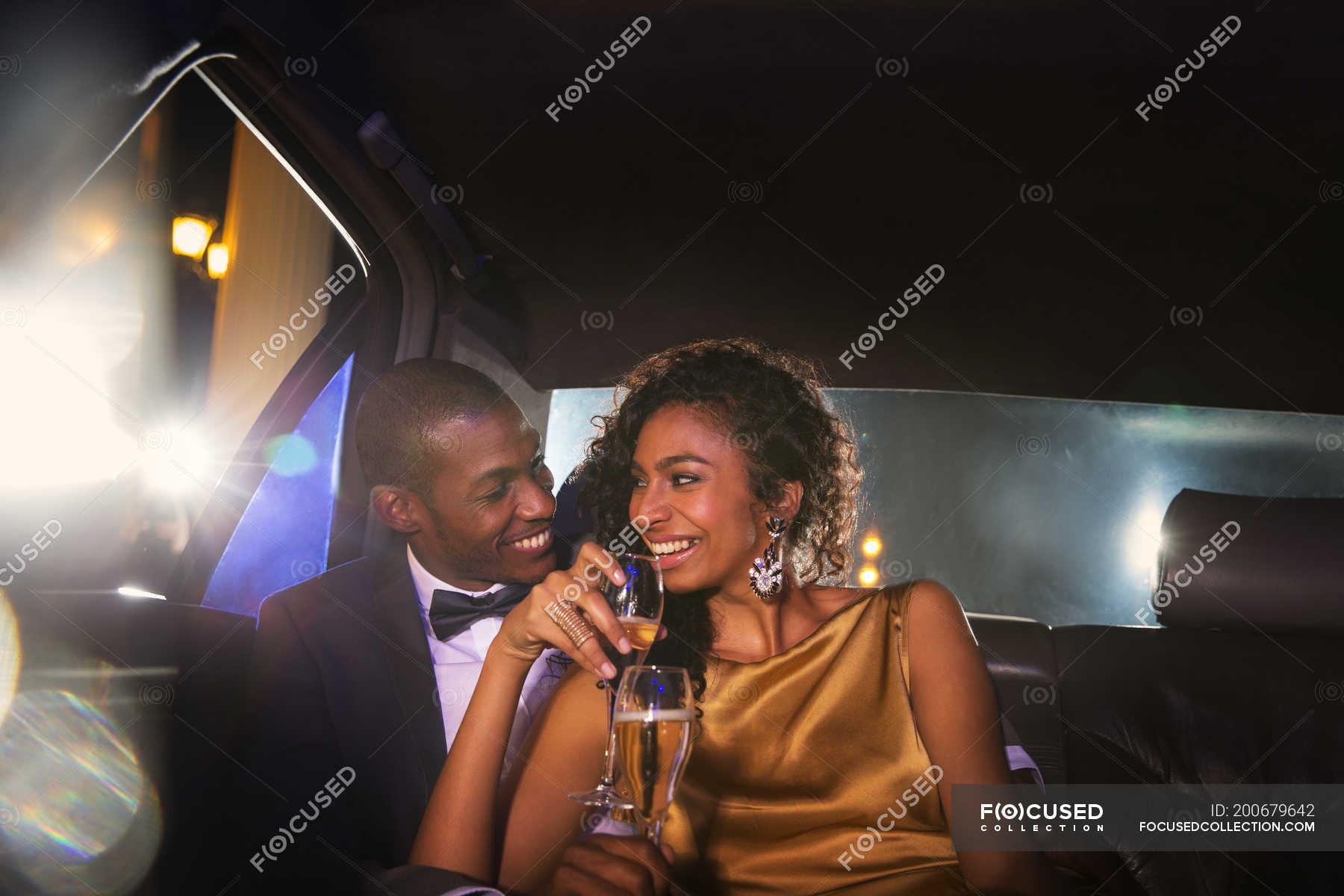 Celebrity couple drinking champagne inside limousine outside event ...