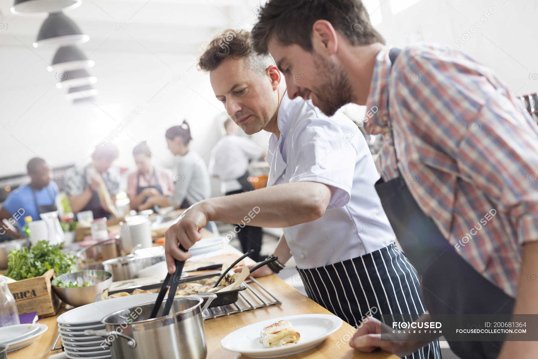 student-watching-chef-teacher-in-cooking-class-kitchen-helping