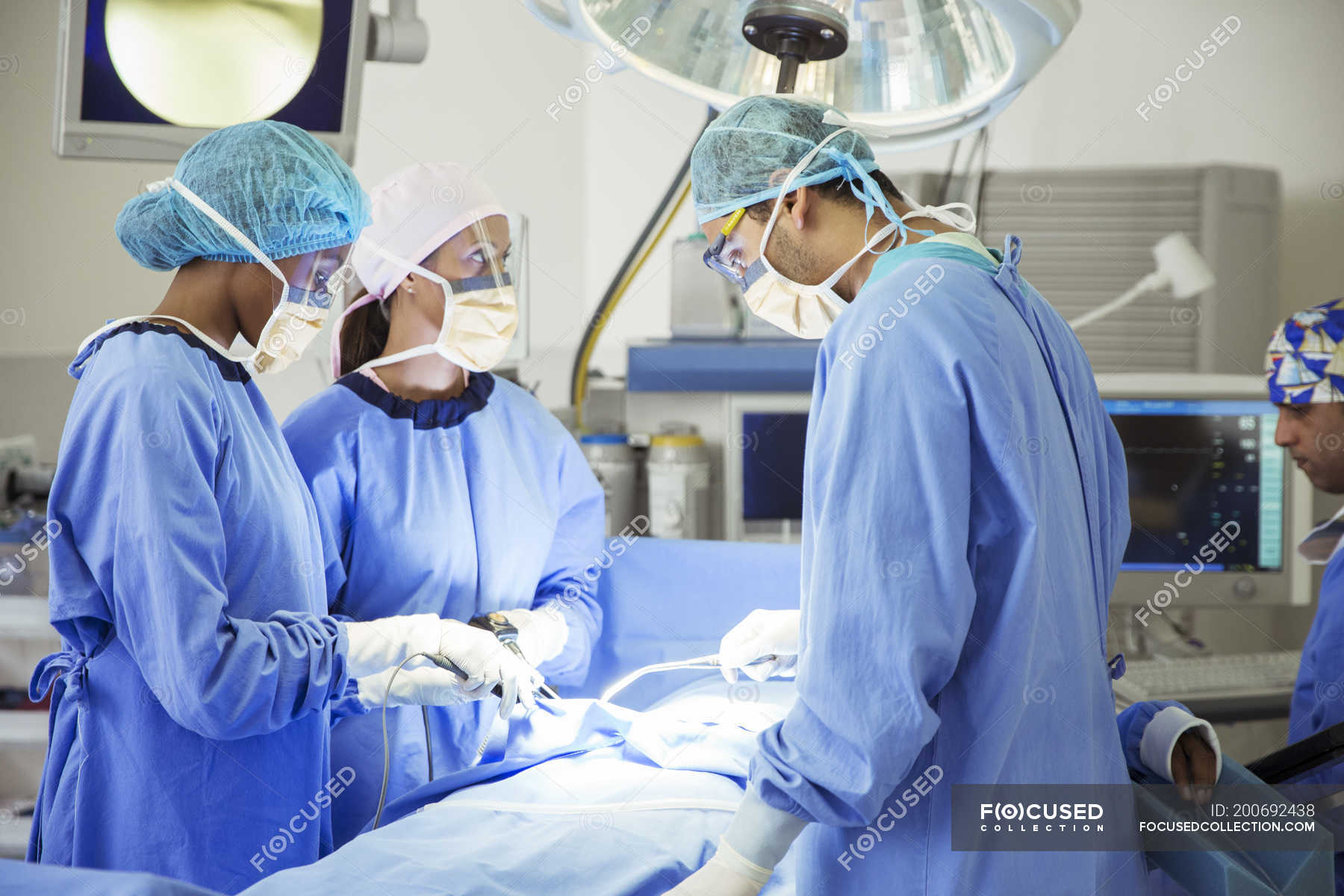 Surgeons performing surgery in operating room — head and shoulders ...