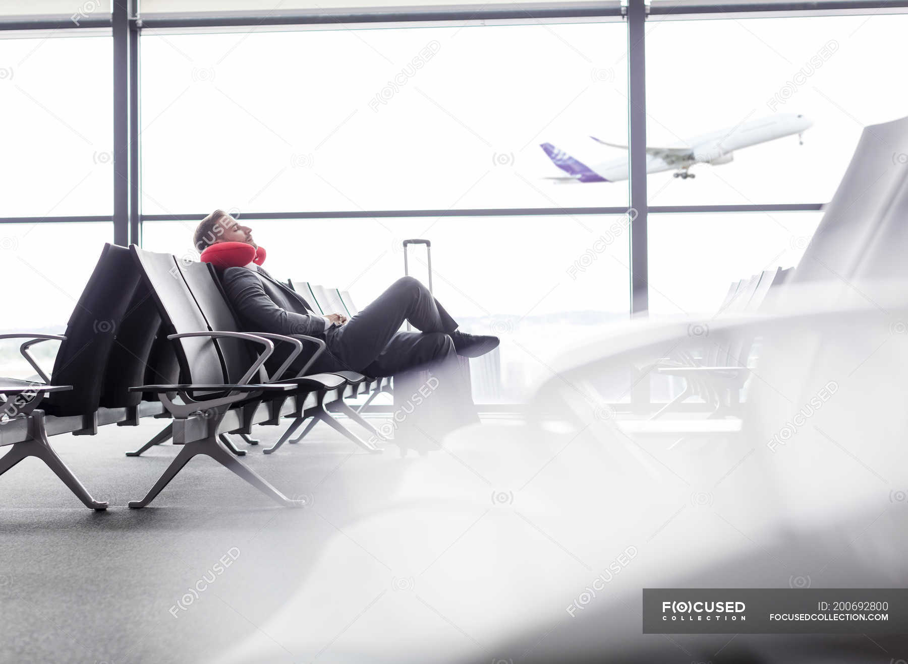 Businessman resting with neck pillow in airport departure area