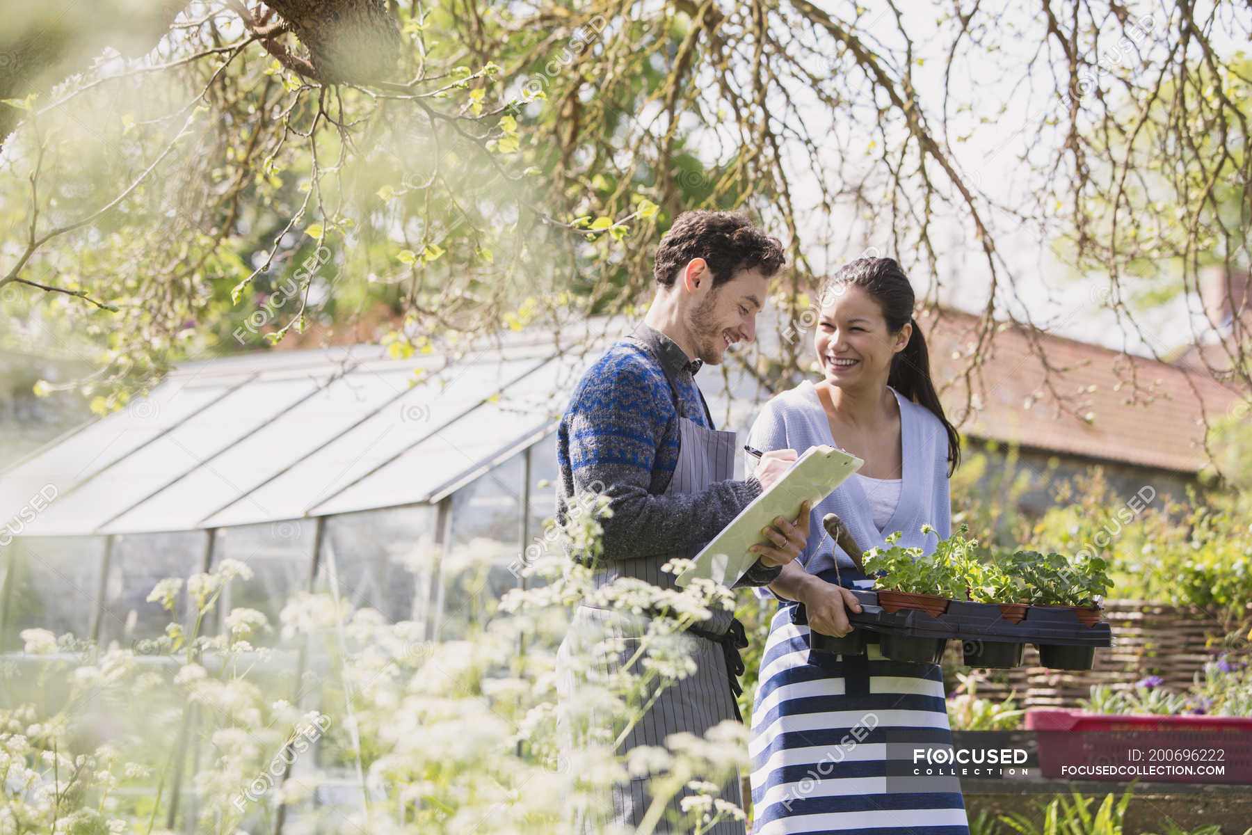 plant-nursery-workers-with-clipboard-and-potted-plants-in-sunny-garden