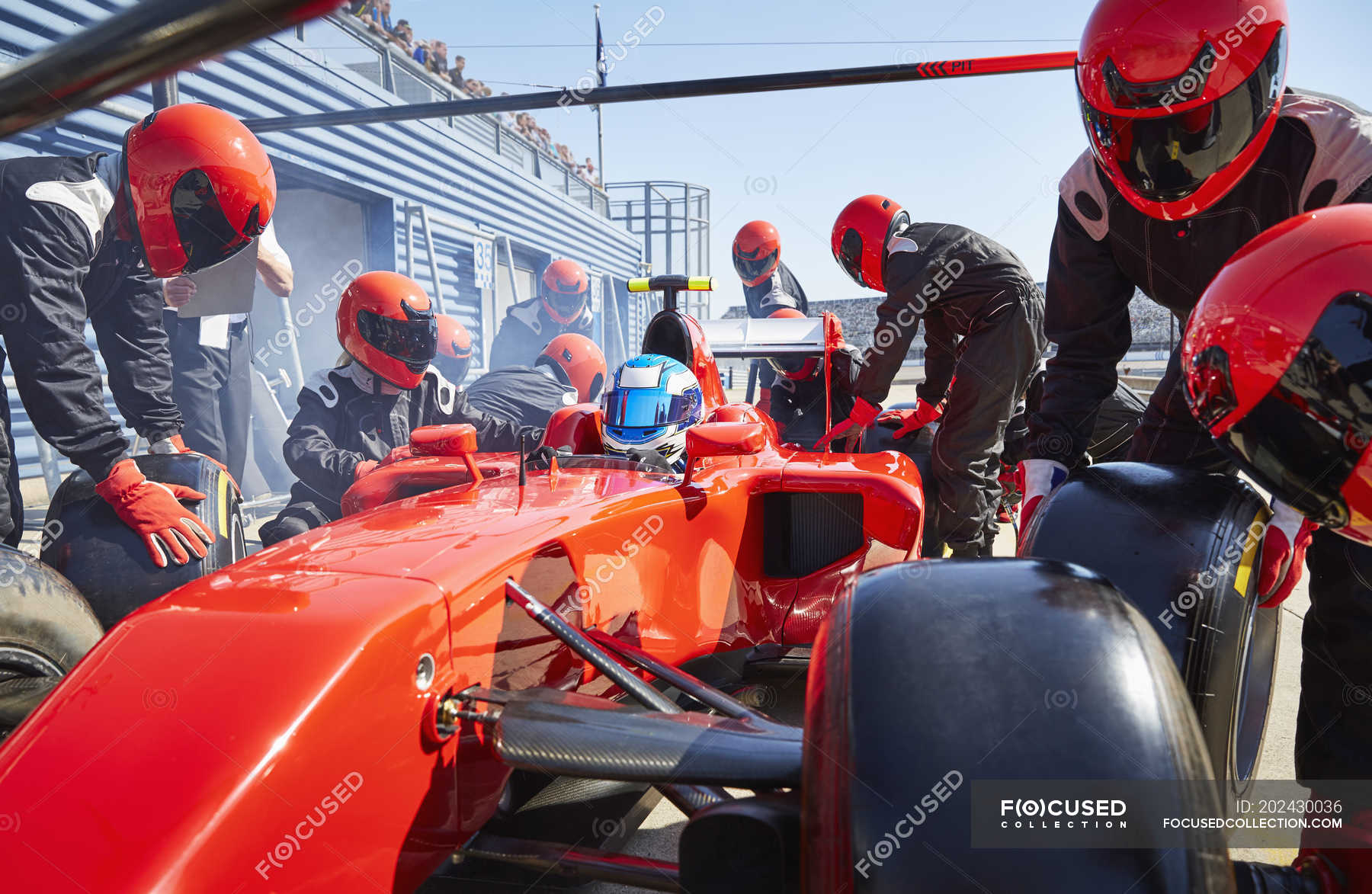 Pit crew replacing tires on formula one race car in pit lane — outside ...