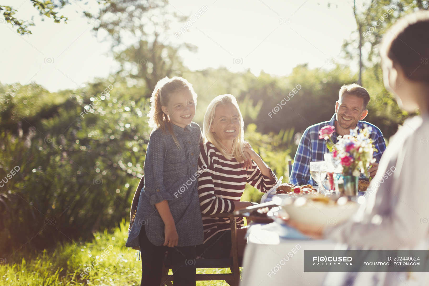 Happy Family Enjoying Lunch At Sunny Garden Party Patio Table