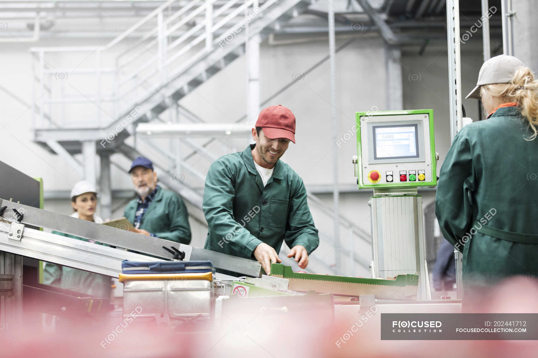 Smiling worker at conveyor belt in food processing plant — uniform