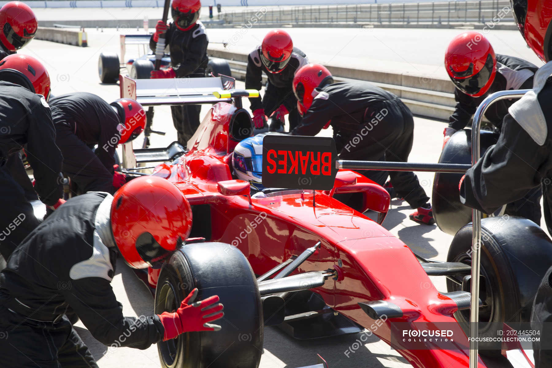 Pit crew replacing tires on formula one race car in pit lane ...