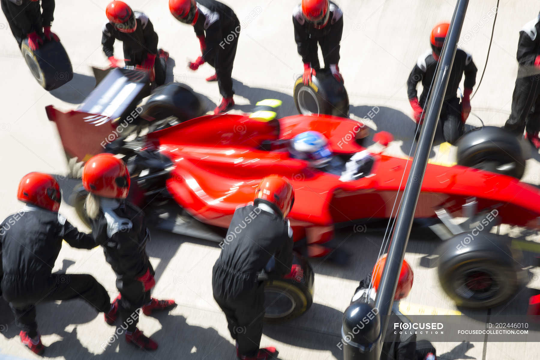 Pit crew replacing tires on formula one race car in pit lane — driving