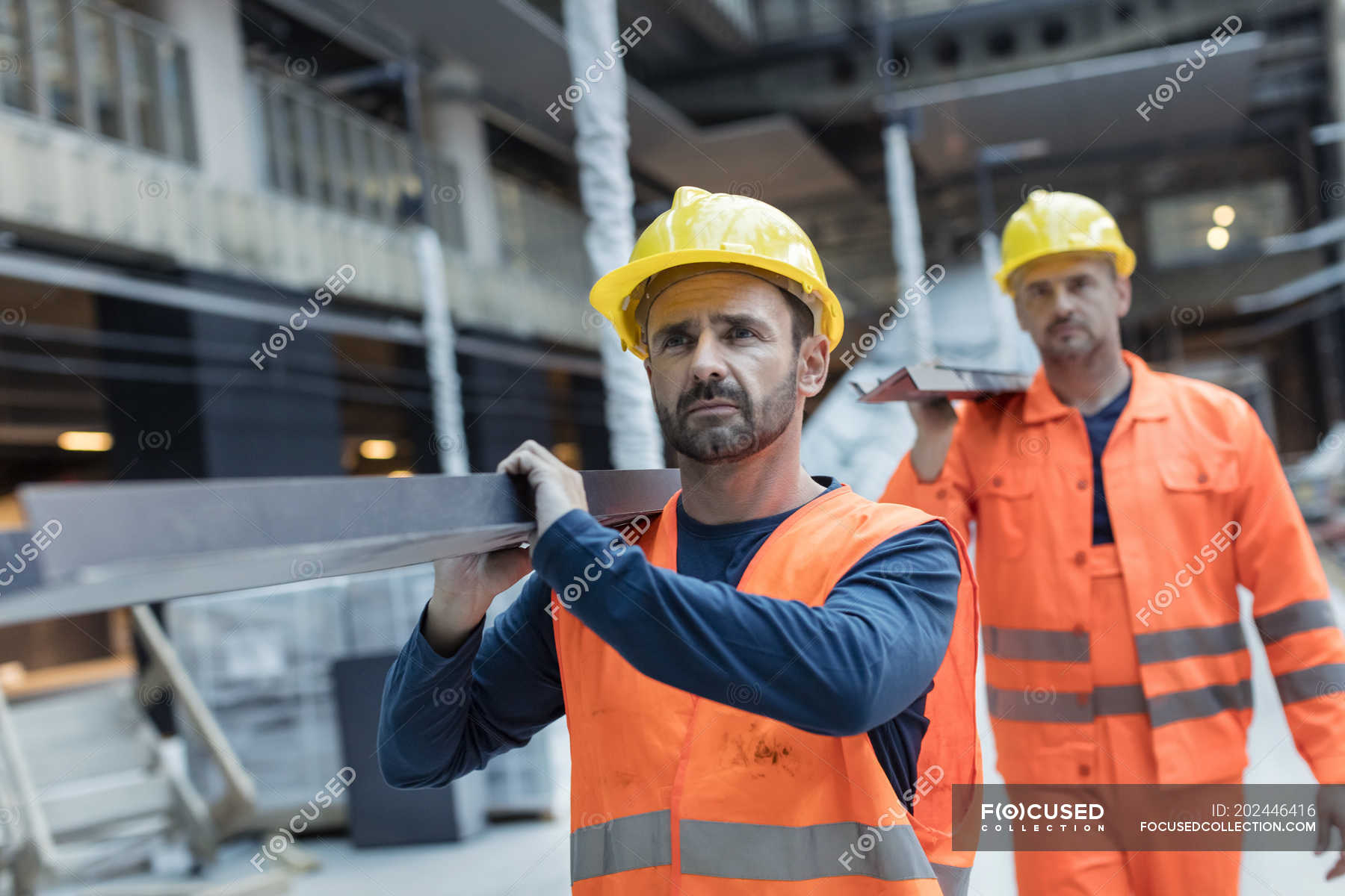 Construction workers carrying metal at construction site — blue collar ...