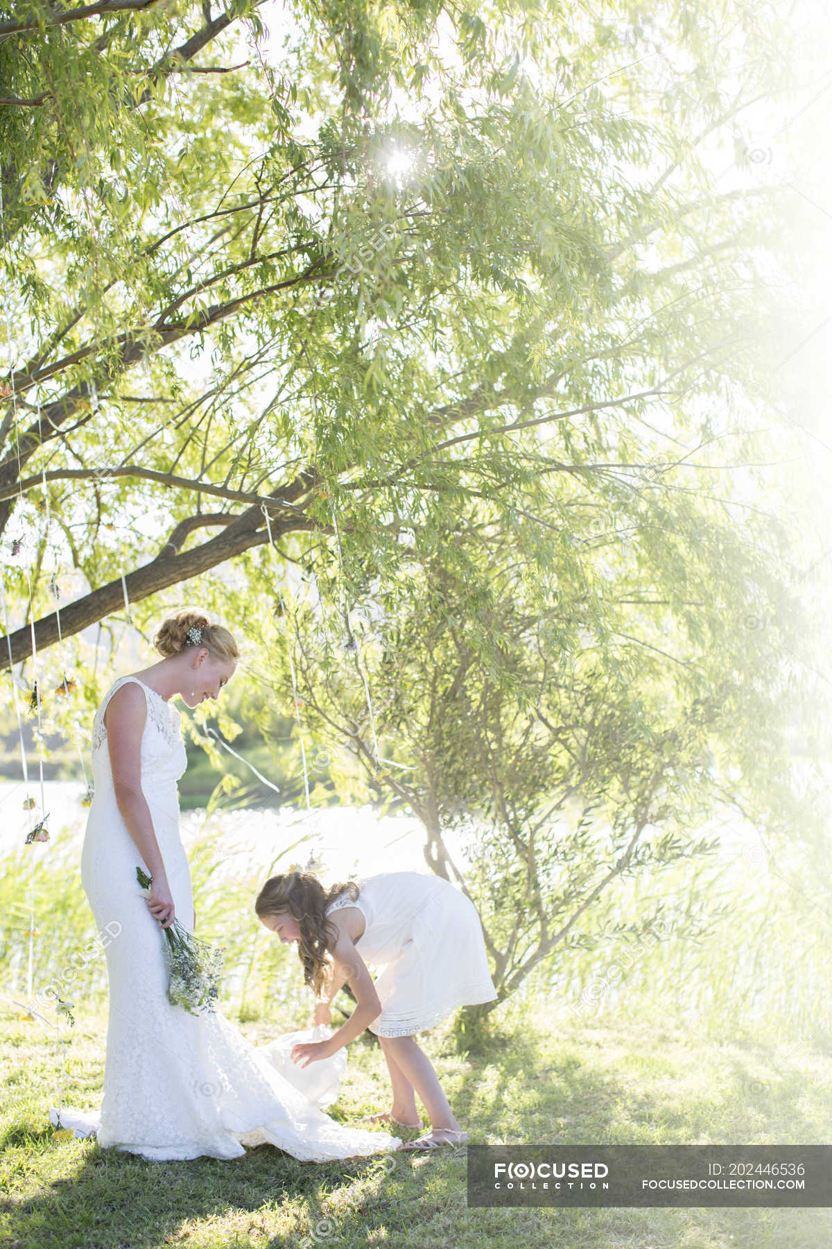 Bride And Bridesmaid Standing In Domestic Garden During Wedding