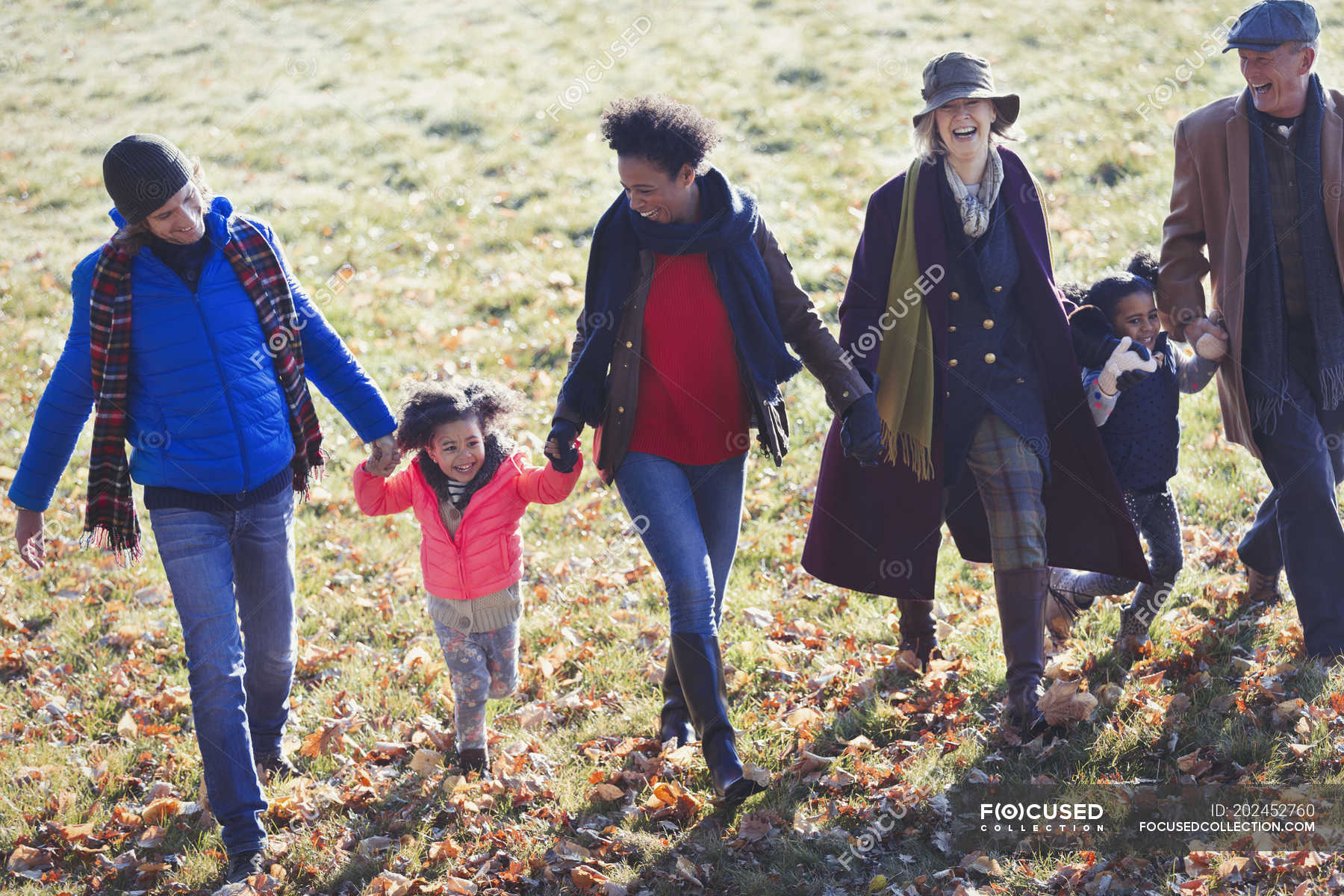 Multi-generation family holding hands and walking in sunny autumn park ...