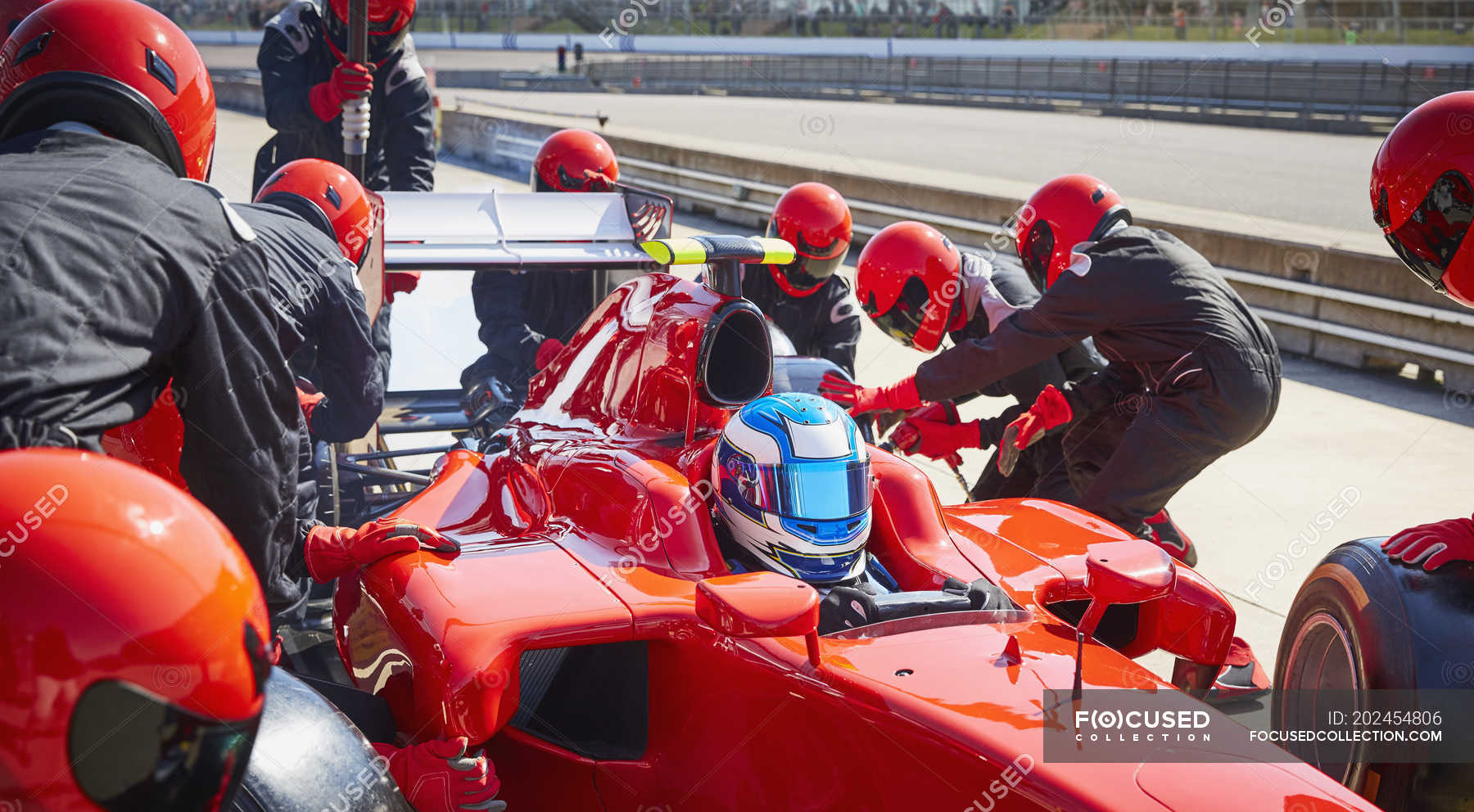 Pit crew replacing tires on formula one race car in pit lane — drive ...