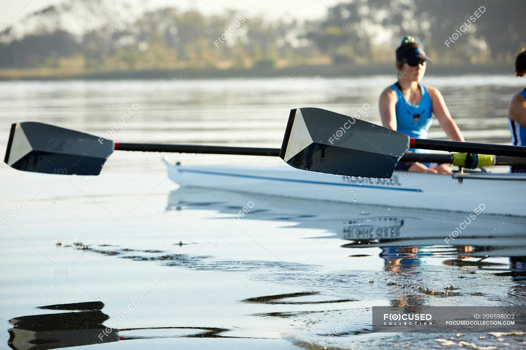 Female rower with oar rowing scull on lake — people, water Stock Photo 209598002