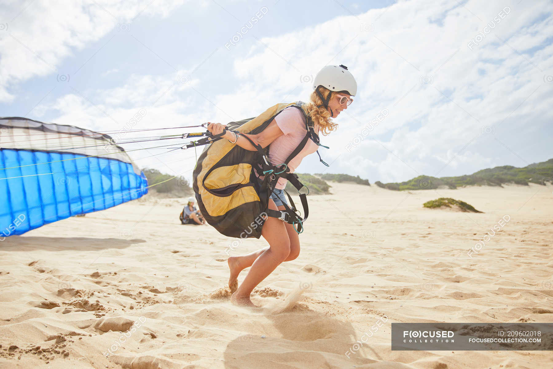 Female paraglider running with parachute on sunny beach — extreme