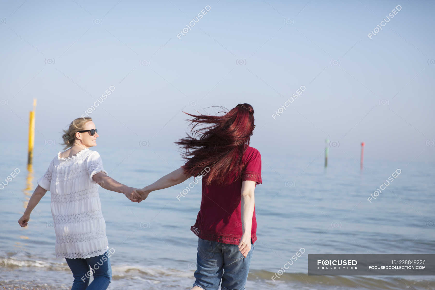 Affectionate Lesbian Couple Holding Hands On Sunny Ocean Beach