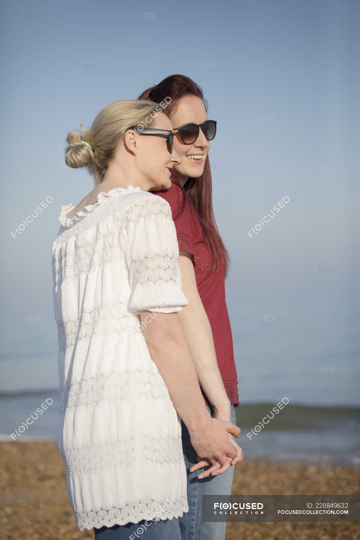Affectionate Lesbian Couple Holding Hands On Sunny Beach — Three Quarter Length Two People
