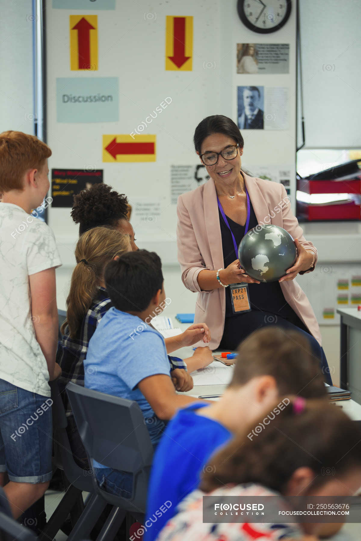 Female Geography Teacher With Globe Teaching Lesson In Classroom ...