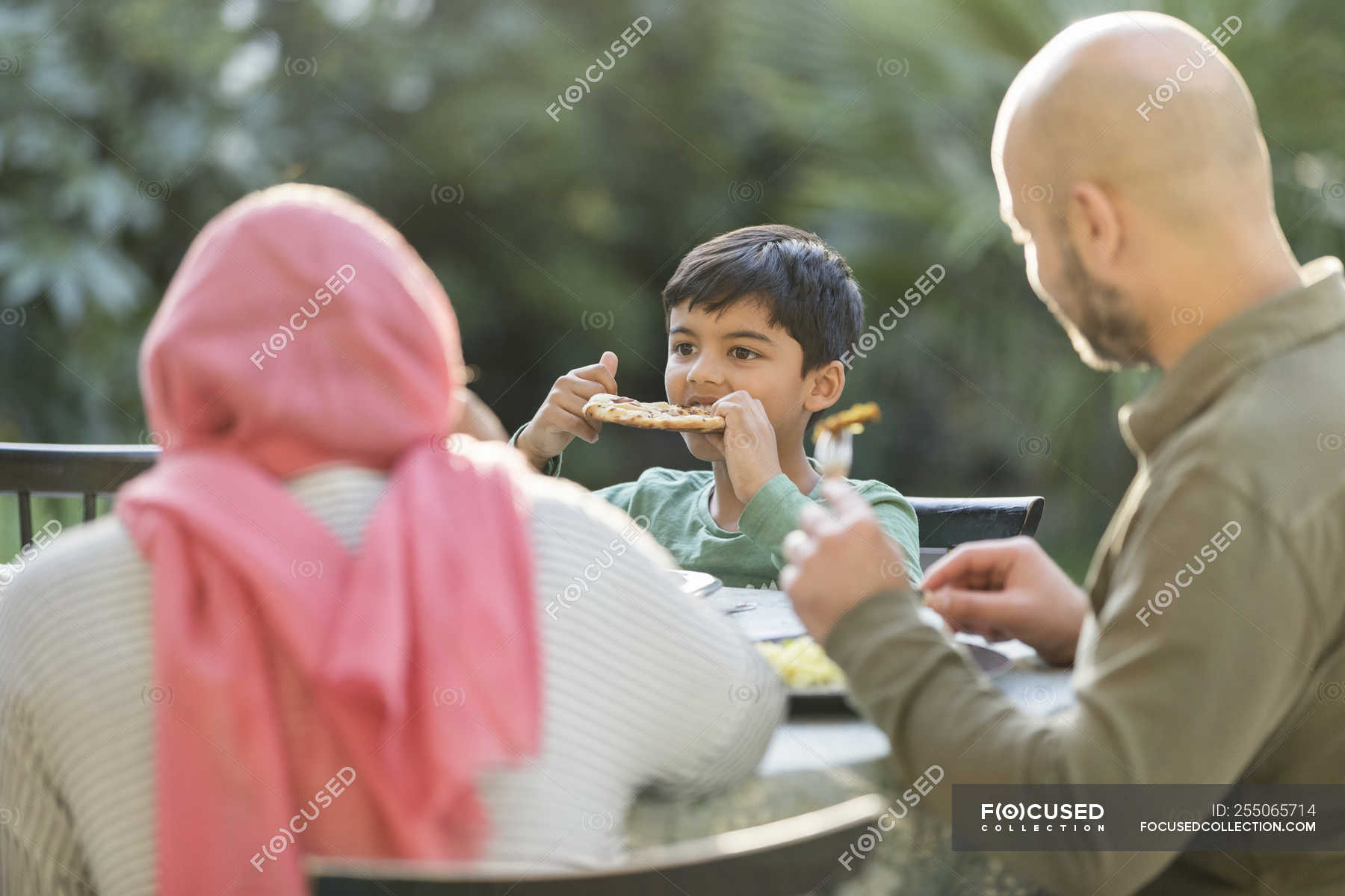 family-eating-dinner-at-patio-table-three-people-naan-bread-stock