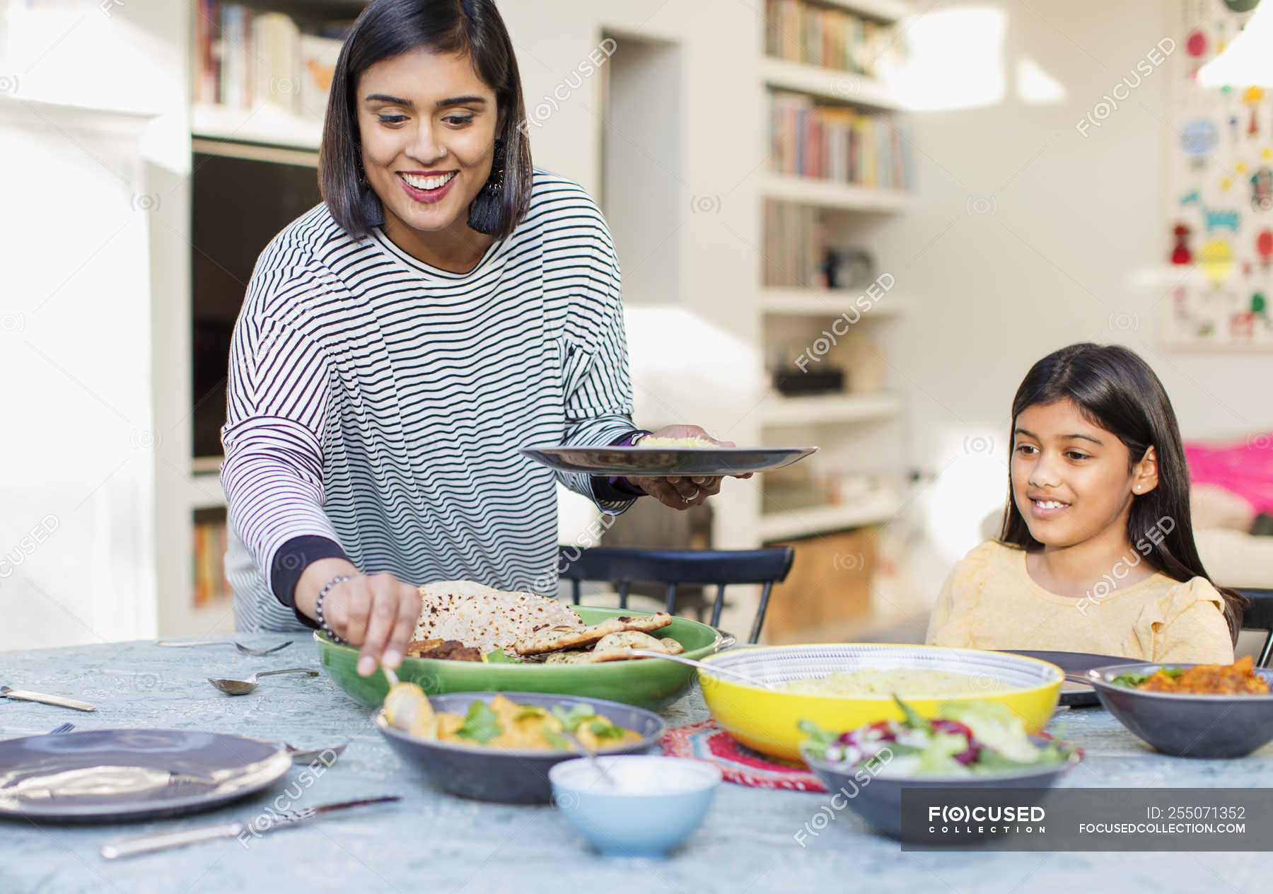 Mother serving dinner to family at dining table — meal, wife Stock