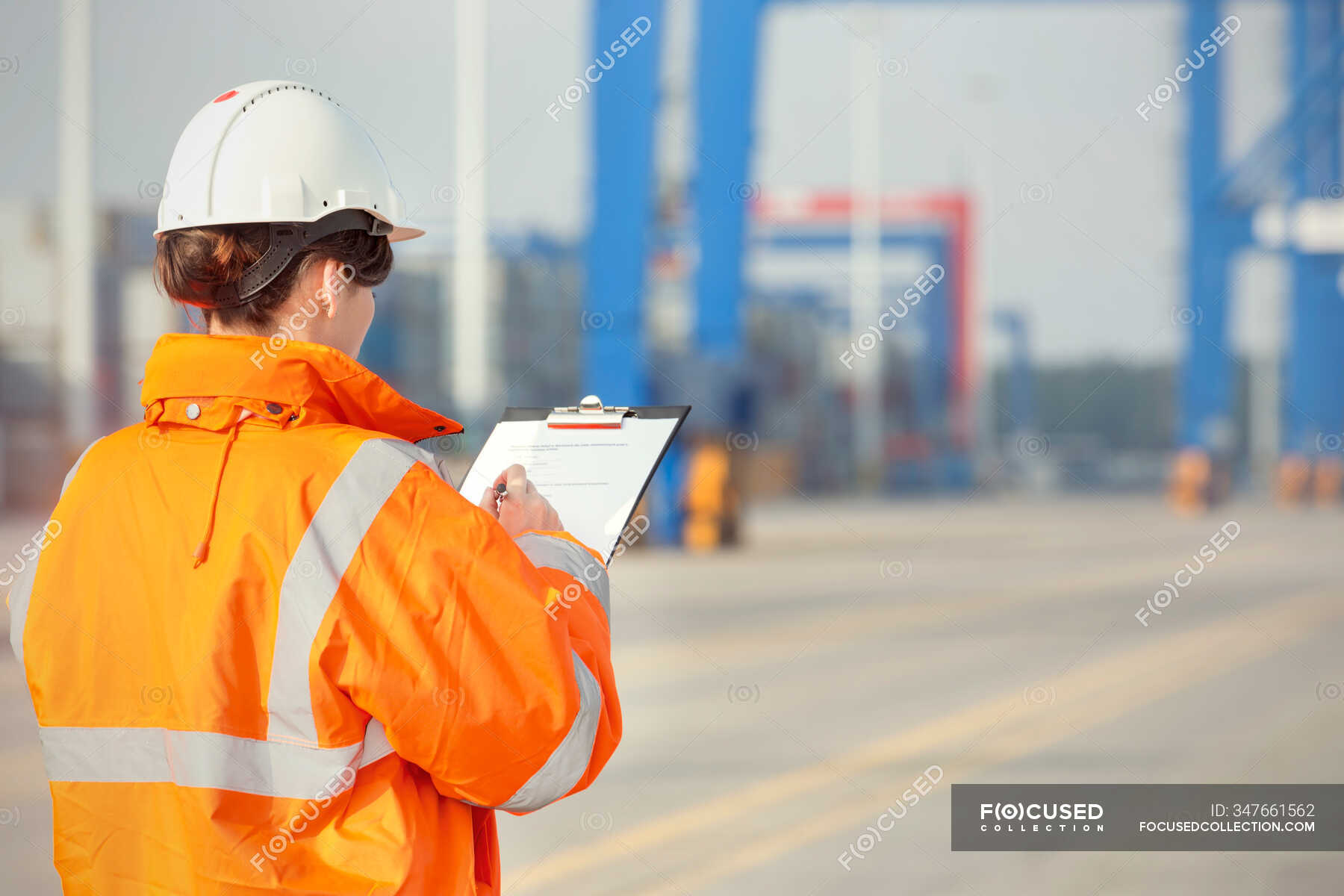 female-dock-worker-with-clipboard-at-shipyard-one-person-day-stock